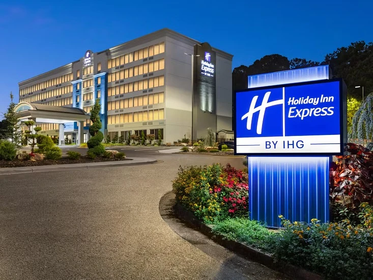 The image shows a well-lit Holiday Inn Express hotel exterior with a prominent entrance sign during twilight.