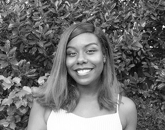 A black and white photo of a woman smiling outside