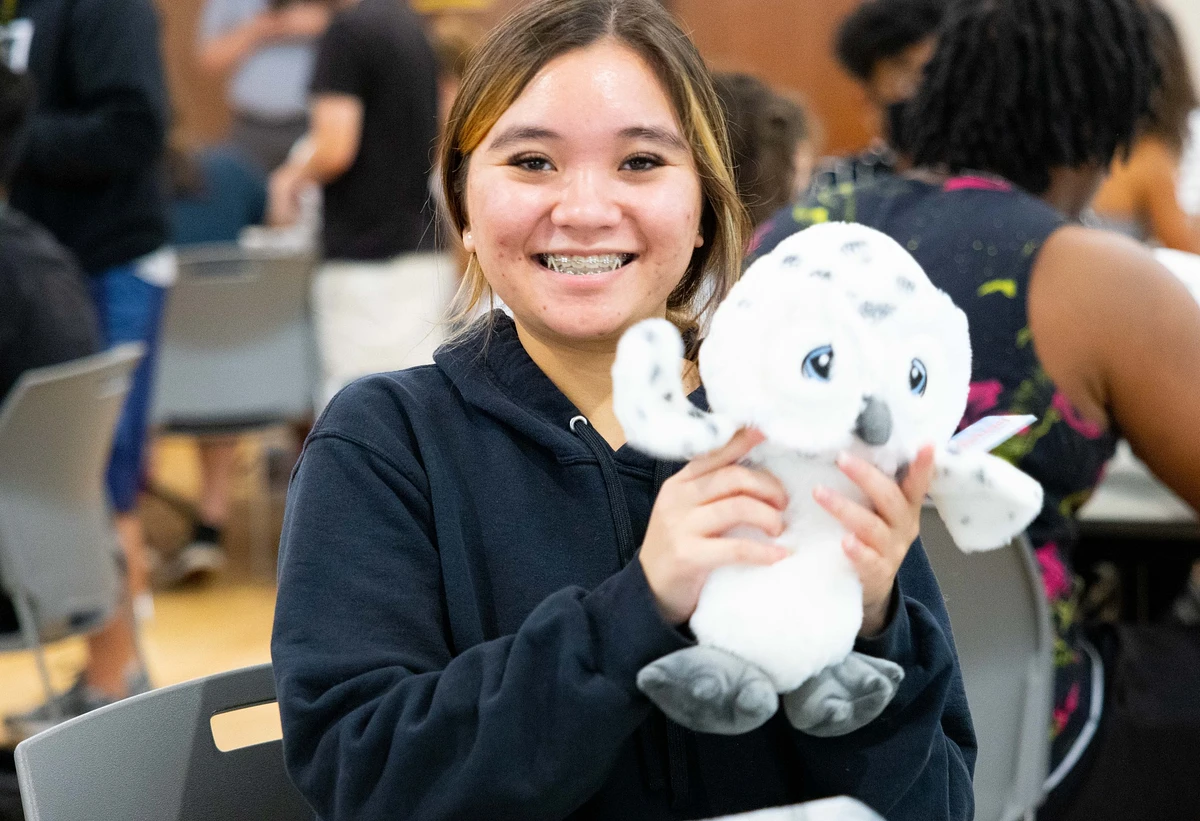 Student holding a white stuffed owl.